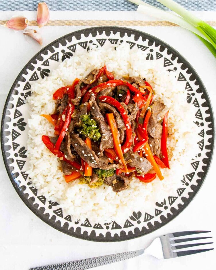 beef stir fry over white rice in a plate