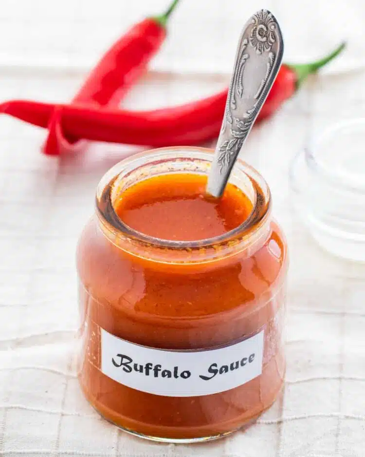 a jar with buffalo wing sauce with a spoon inside it