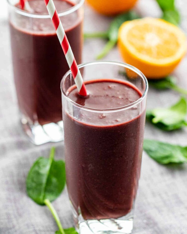 two glasses with a straw inside filled with freshly made açai smoothie