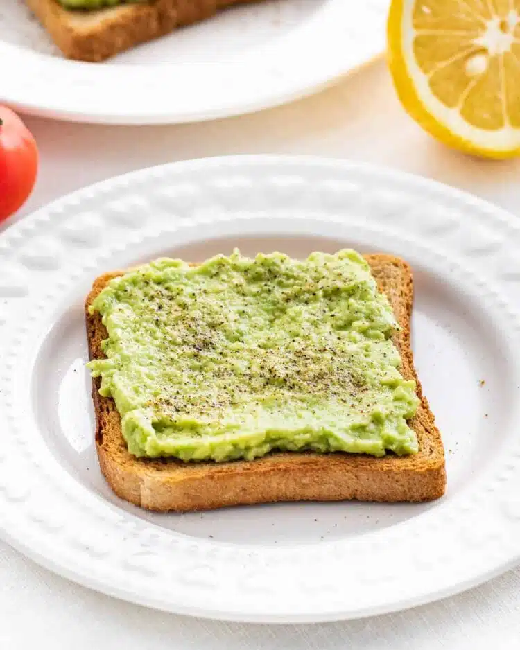 a slice of avocado toast on a white plate