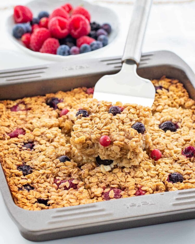 a spatula lifting a slice of baked oatmeal from a pan 
