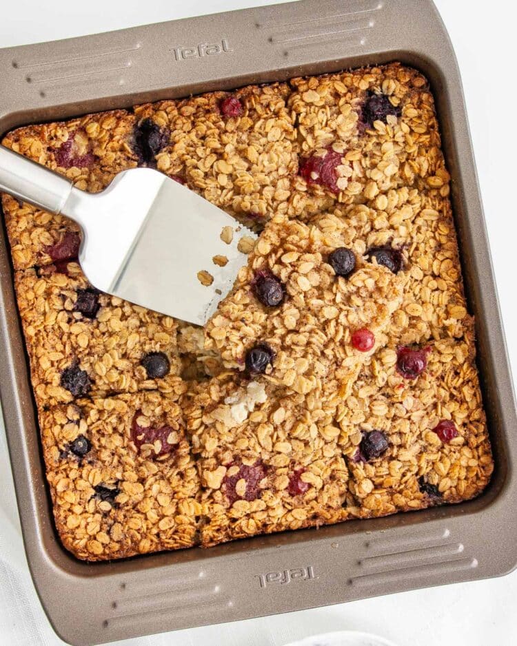 overhead shot of a pan with baked oatmeal and a spatula lifting a slice out