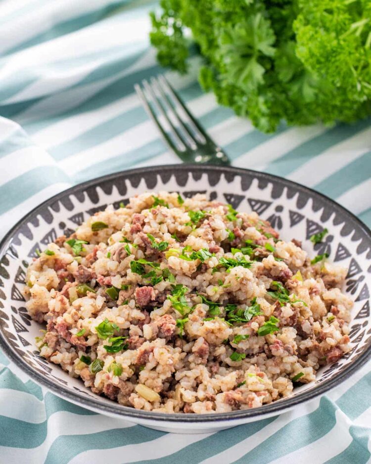 a bowl of dirty rice garnished with parsley