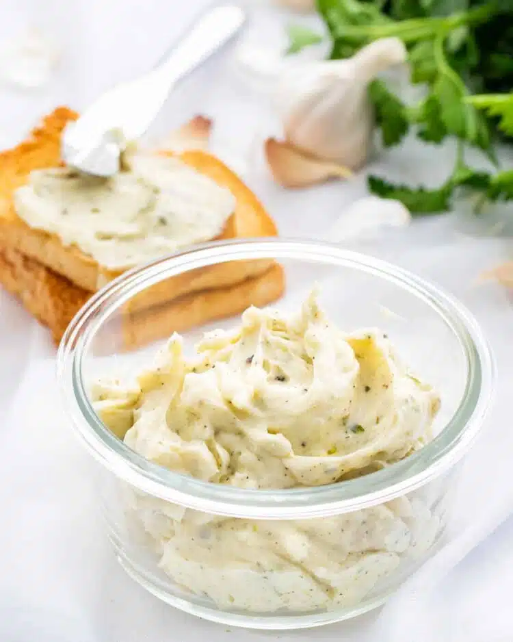 garlic butter in a glass bowl with two slices of toast in the background