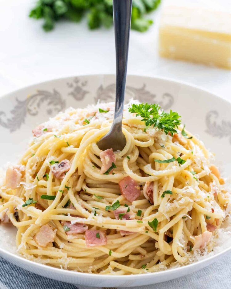 a fork twirling some spaghetti in a plate full of carbonara