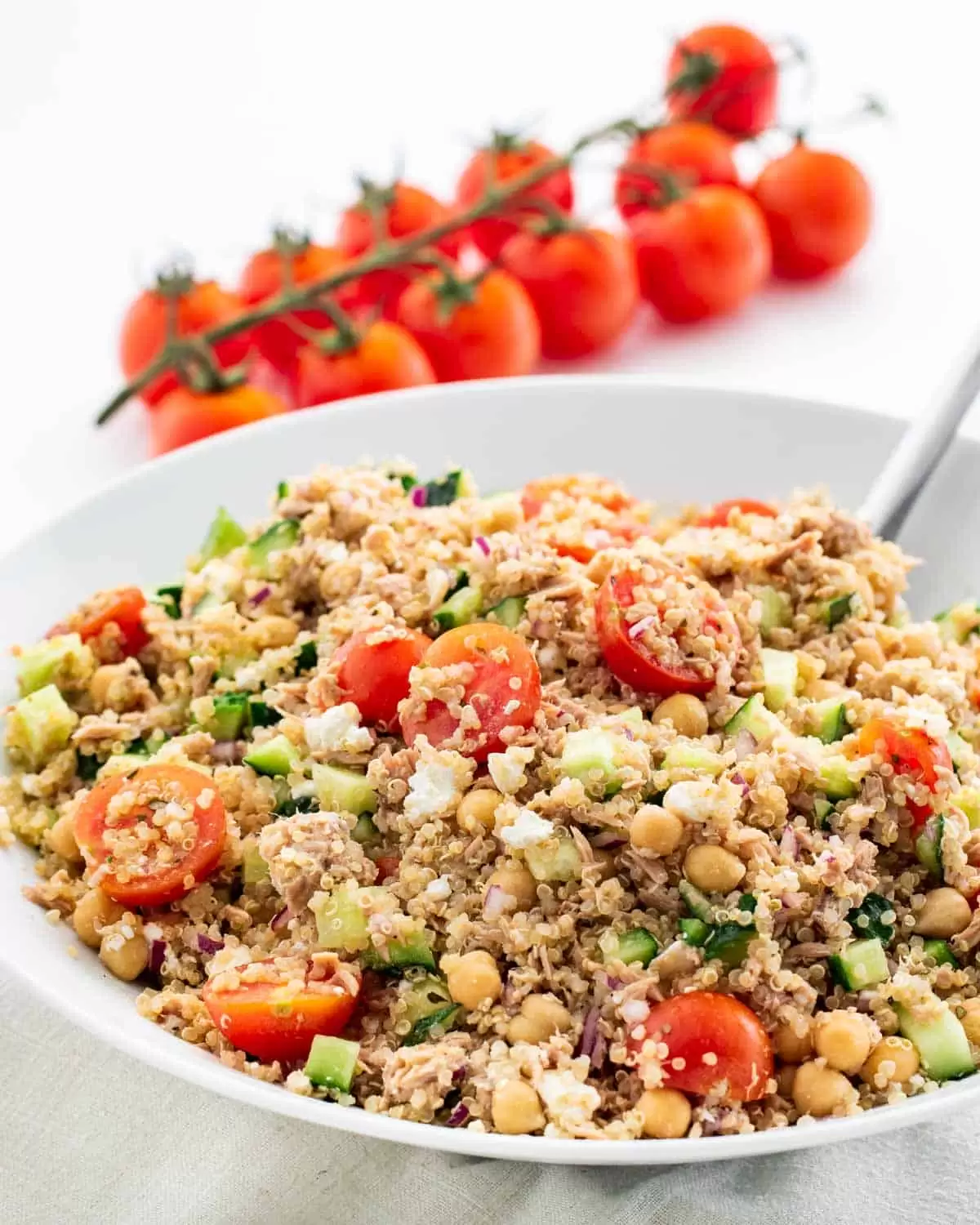 tuna quinoa salad with tomatoes and cucumbers in a white bowl