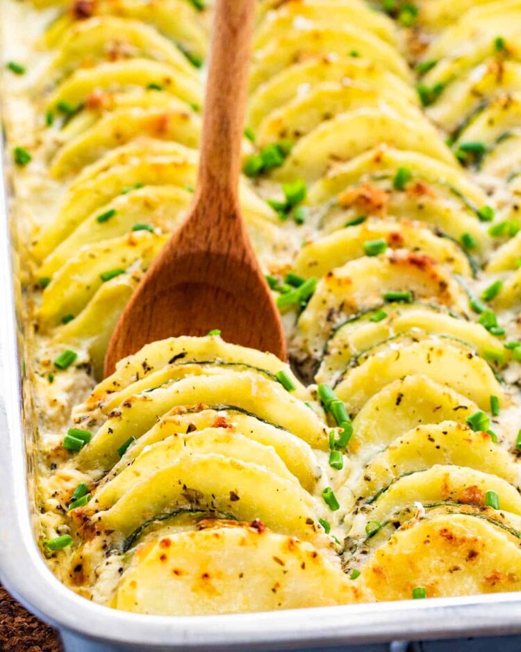 zucchini potato bake in a casserole dish garnished with chives fresh out of the oven