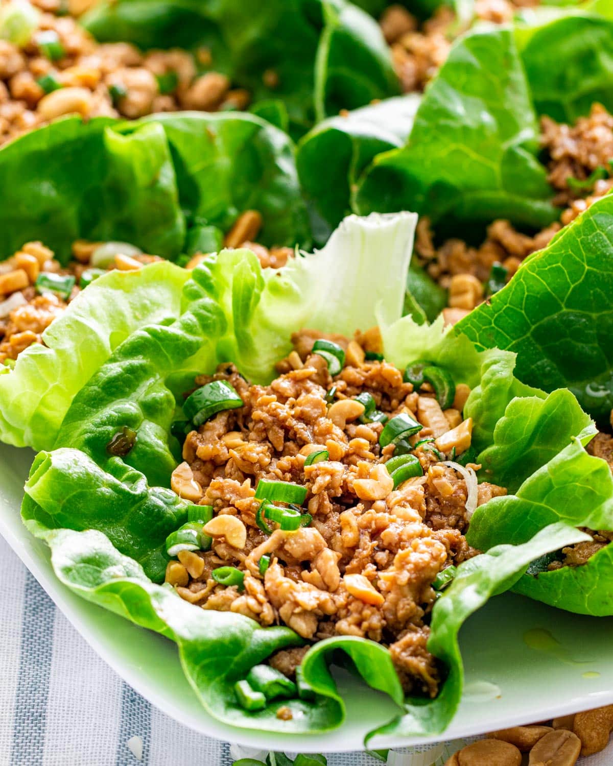 asian lettuce wraps on a white platter garnished with peanuts