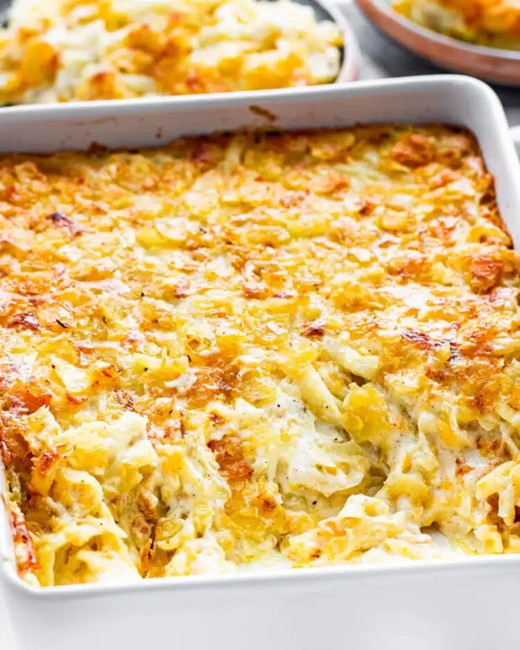 side view shot of cheesy potato casserole in a casserole dish with some already scooped out