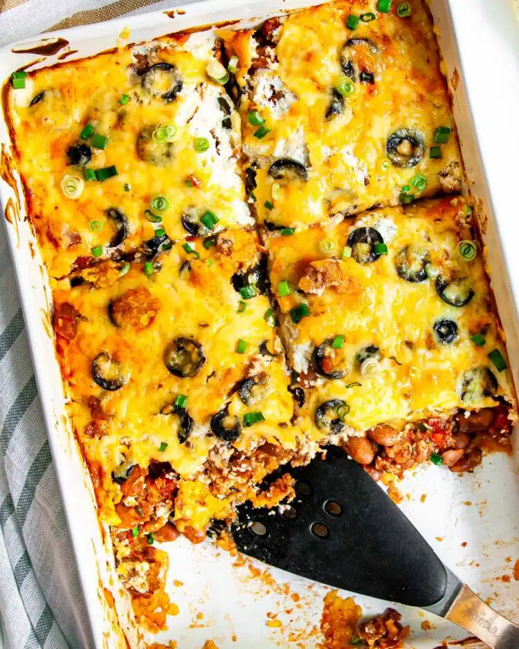 overhead shot of mexican casserole in a casserole dish cut into slice and 2 slices missing 