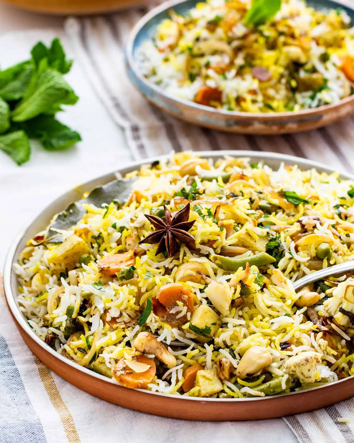 side view shot of a gorgeous plate full of vegetable biryani with a fork in it