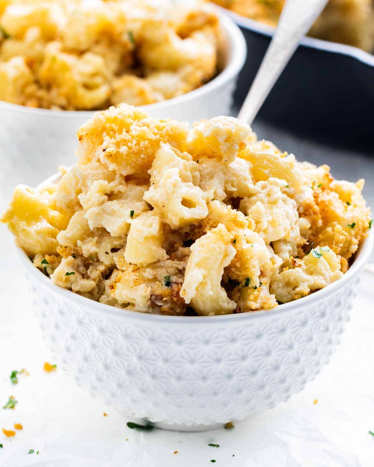 closeup shot of baked mac and cheese in a white bowl with a fork inside