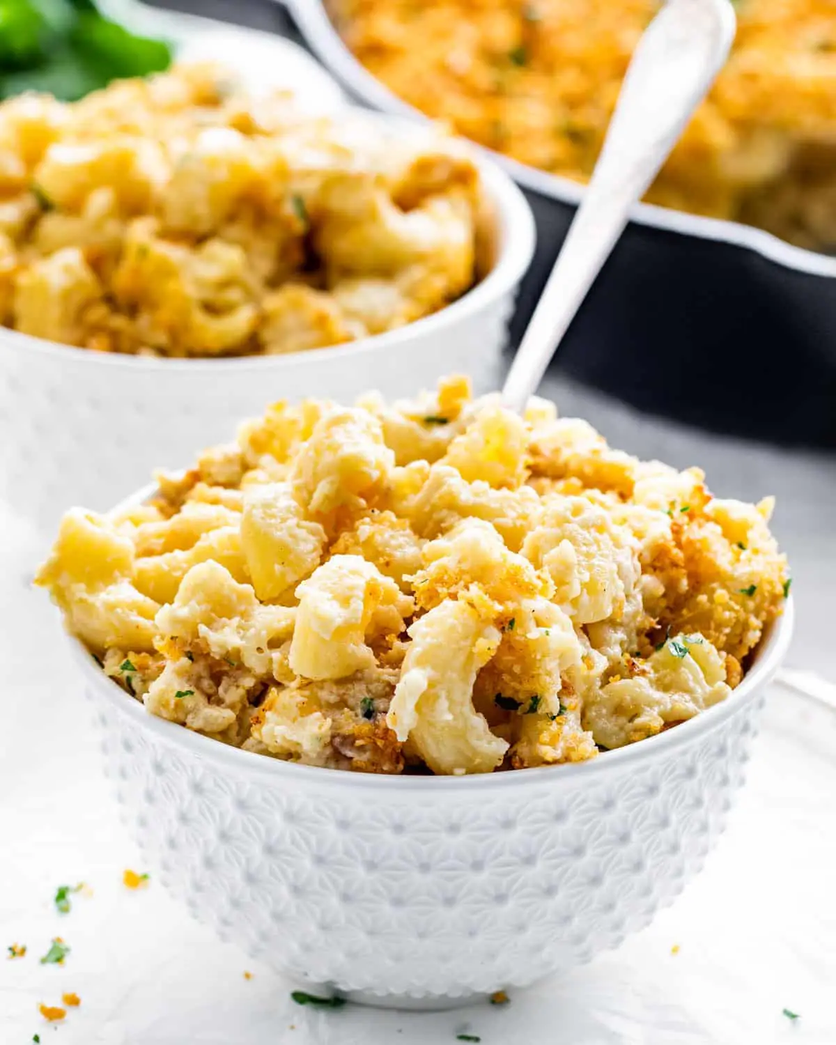 a white bowl filled with baked mac and cheese with a fork inside