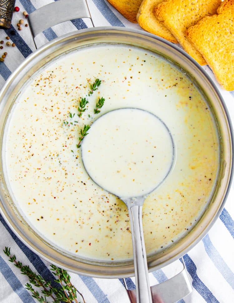 overhead shot of cream of cauliflower soup in a large soup pot with a ladle inside