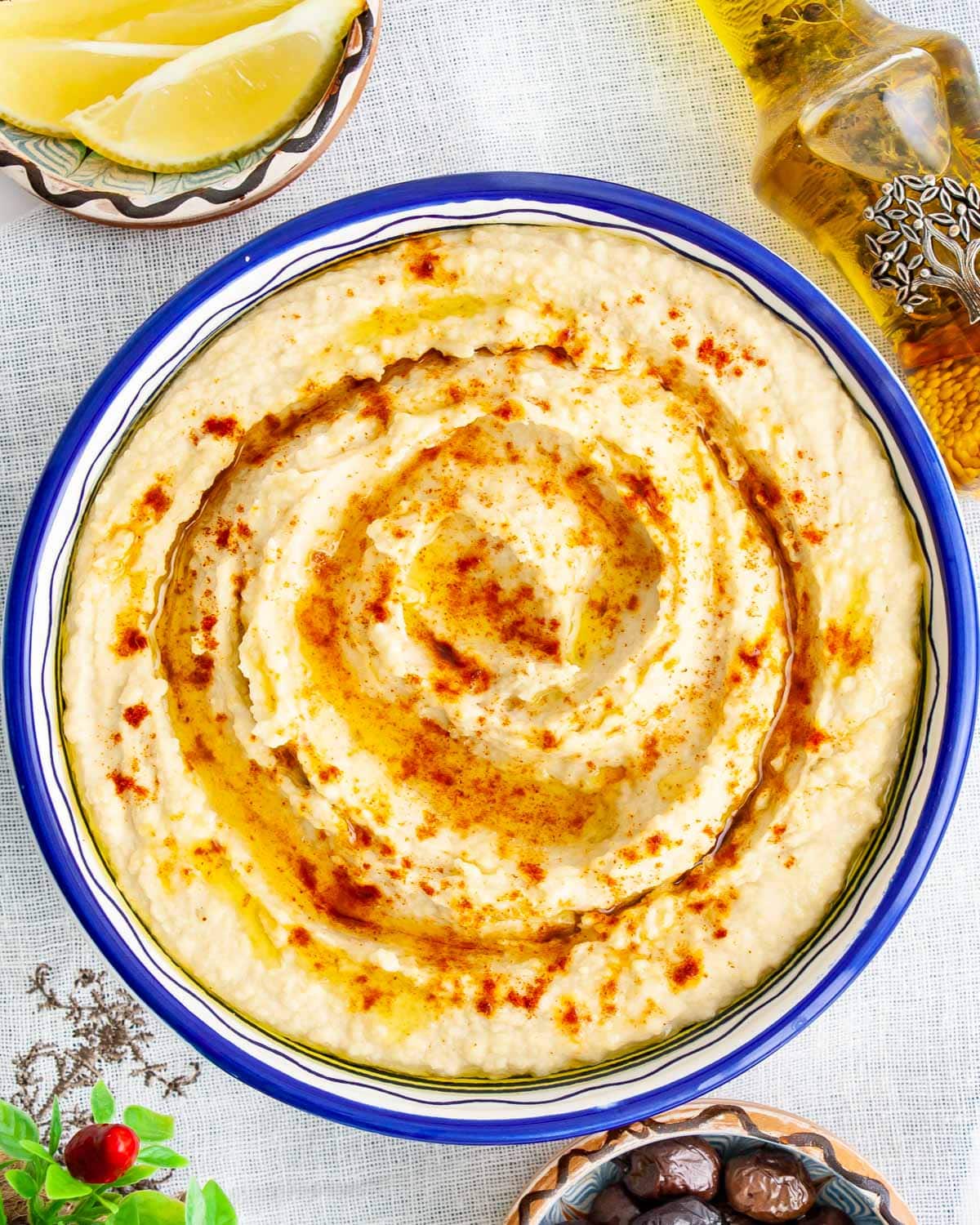 overhead shot of a bowl filled with freshly made hummus drizzled with olive oil and sprinkled with a bit of paprika
