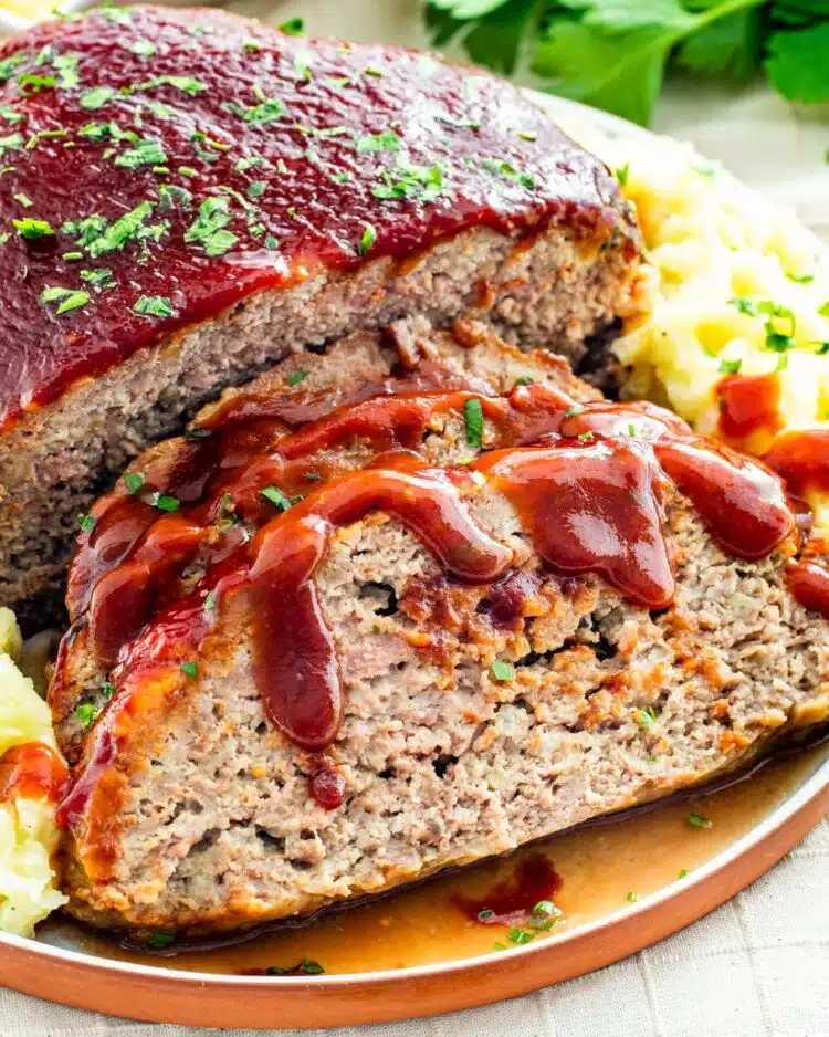 sideview shot of sliced meatloaf with mashed potatoes on a serving platter
