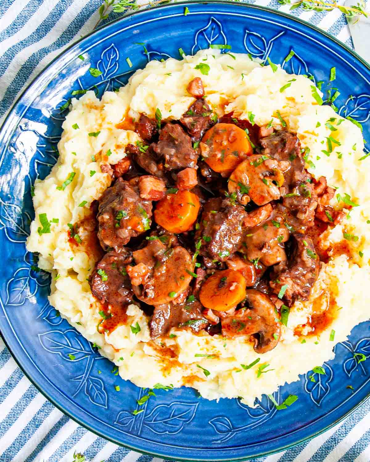 overhead shot of beef stew over mashed potatoes in a blue plate