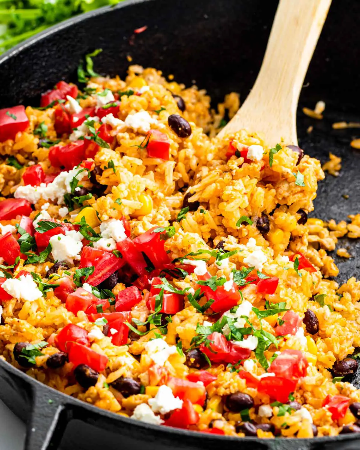 mexican fried rice in a skillet with a wooden spoon