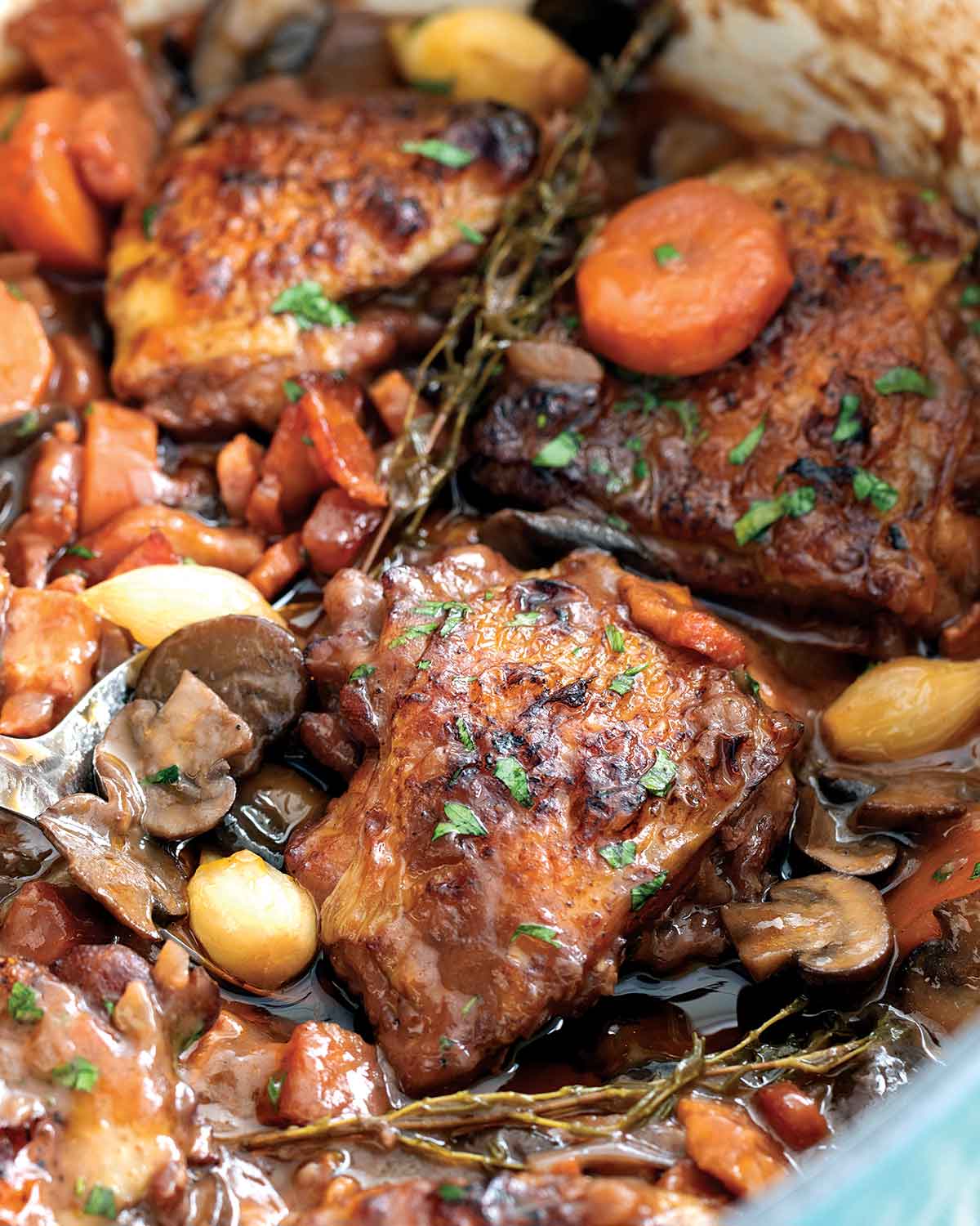 closeup shot of a chicken thigh in a dutch oven full of coq au vin