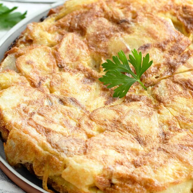 spanish tortilla on a plate with a garnish of parsley.