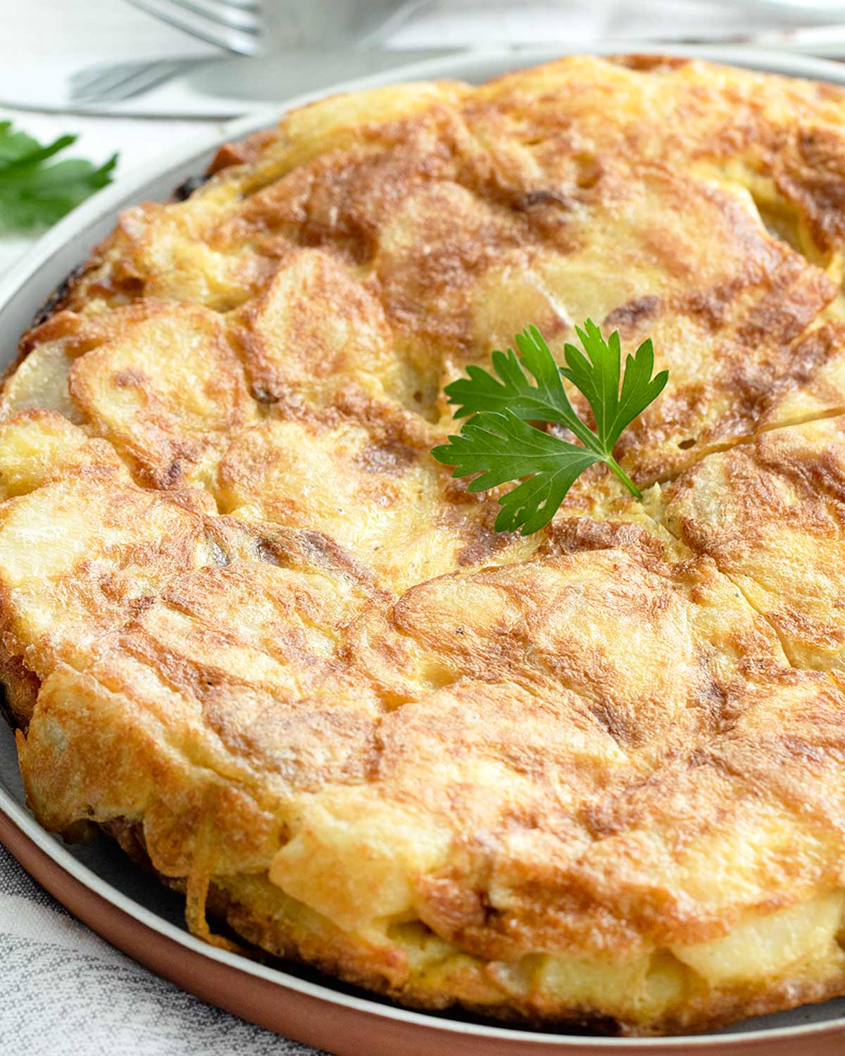 spanish tortilla on a plate with a garnish of parsley.