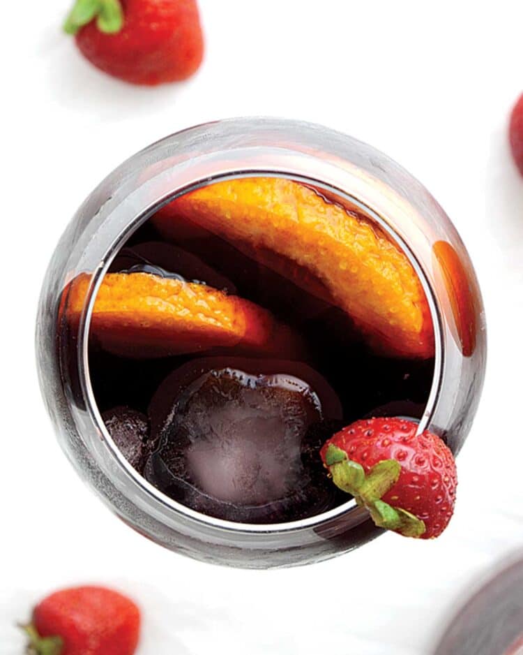 overhead shot of red sangria in a glass and garnished with a strawberry