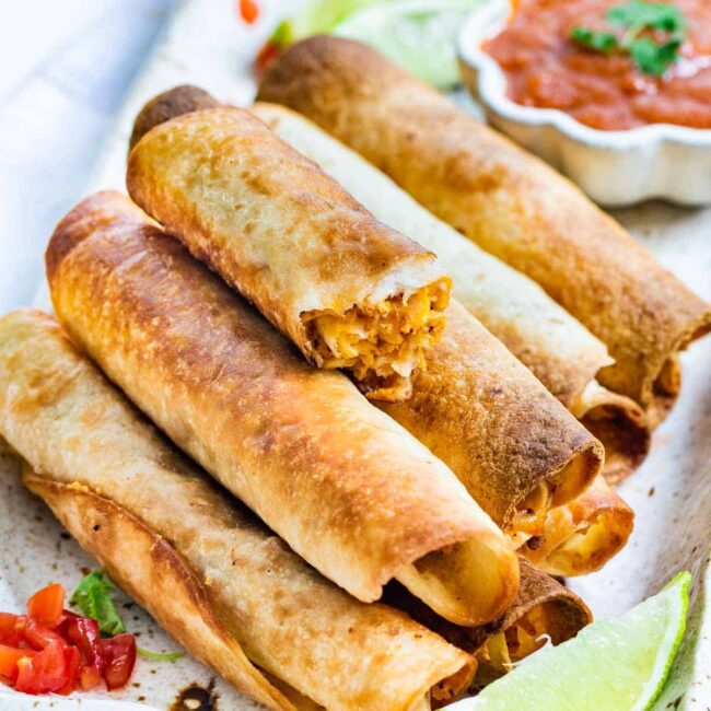 chicken taquitos stacked on top of each other on a serving platter.