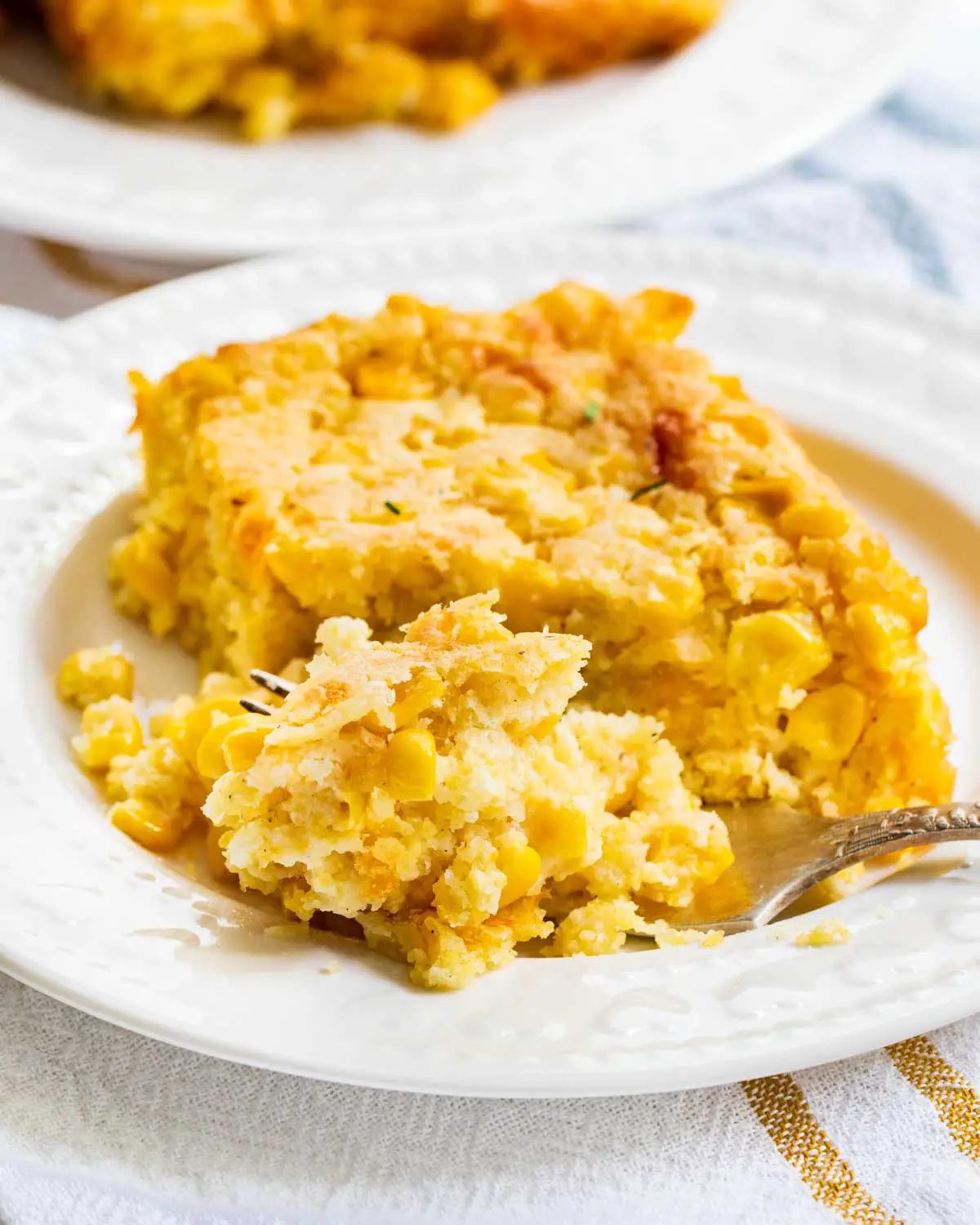 a slice of corn casserole on a plate with a fork.