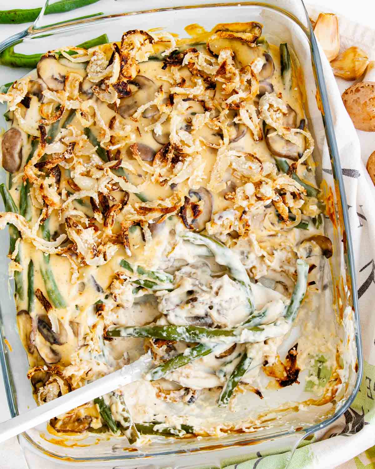 overhead shot of green bean casserole in a casserole dish with a serving spoon inside.