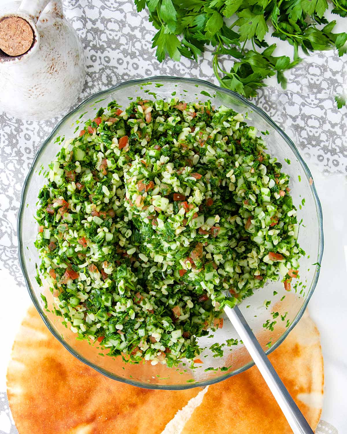 overhead shot of tabbouleh salad freshly made in a bowl with a spoon in it.