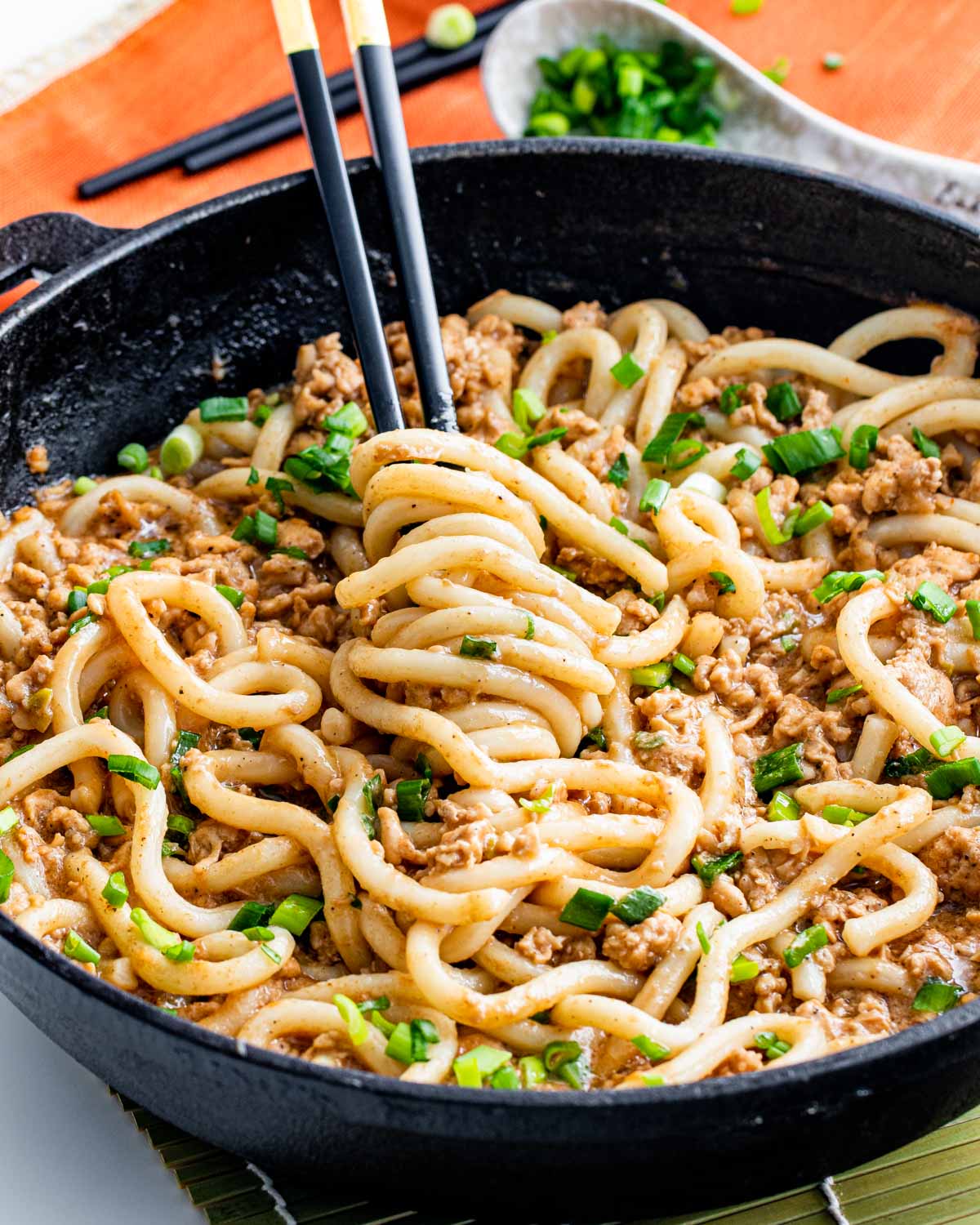 overhead of quick chicken peanut noodles in a skillet with chopsticks twirling some noodles.