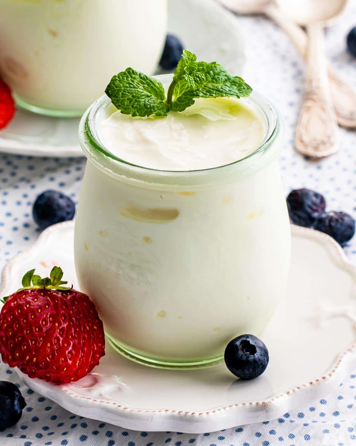 yogurt in a serving jar garnished with mint and berries.