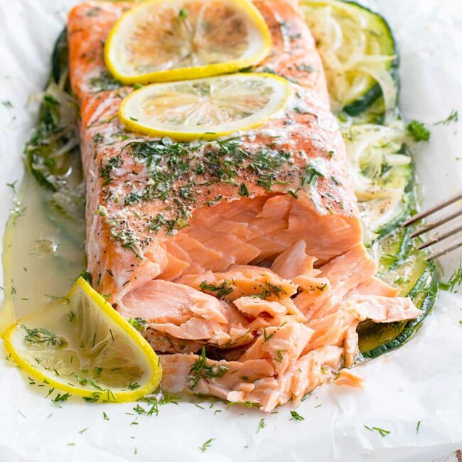 salmon en papillote on a plate flaked with a fork.