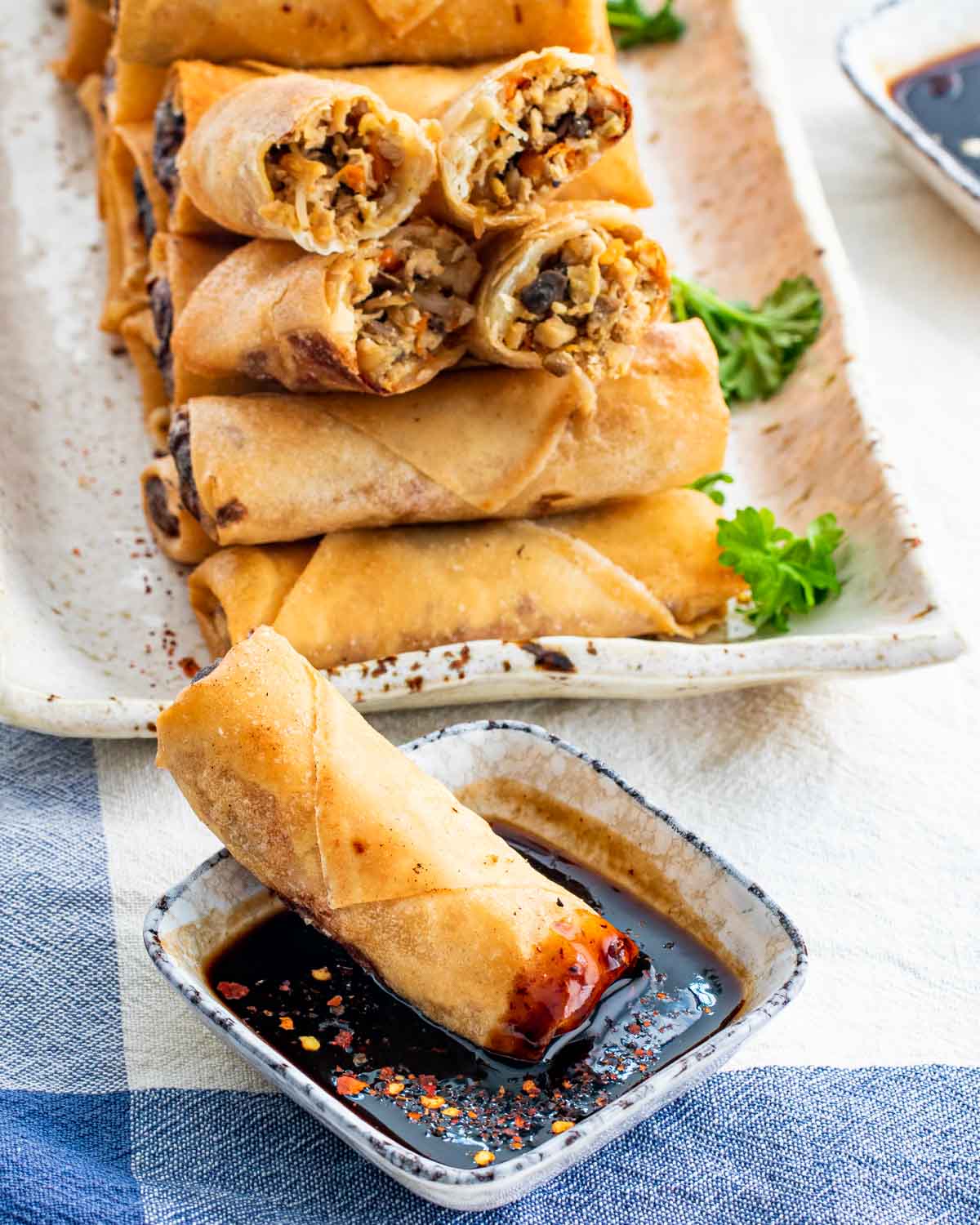 a spring roll dipped in a little bowl with hoisin sauce.