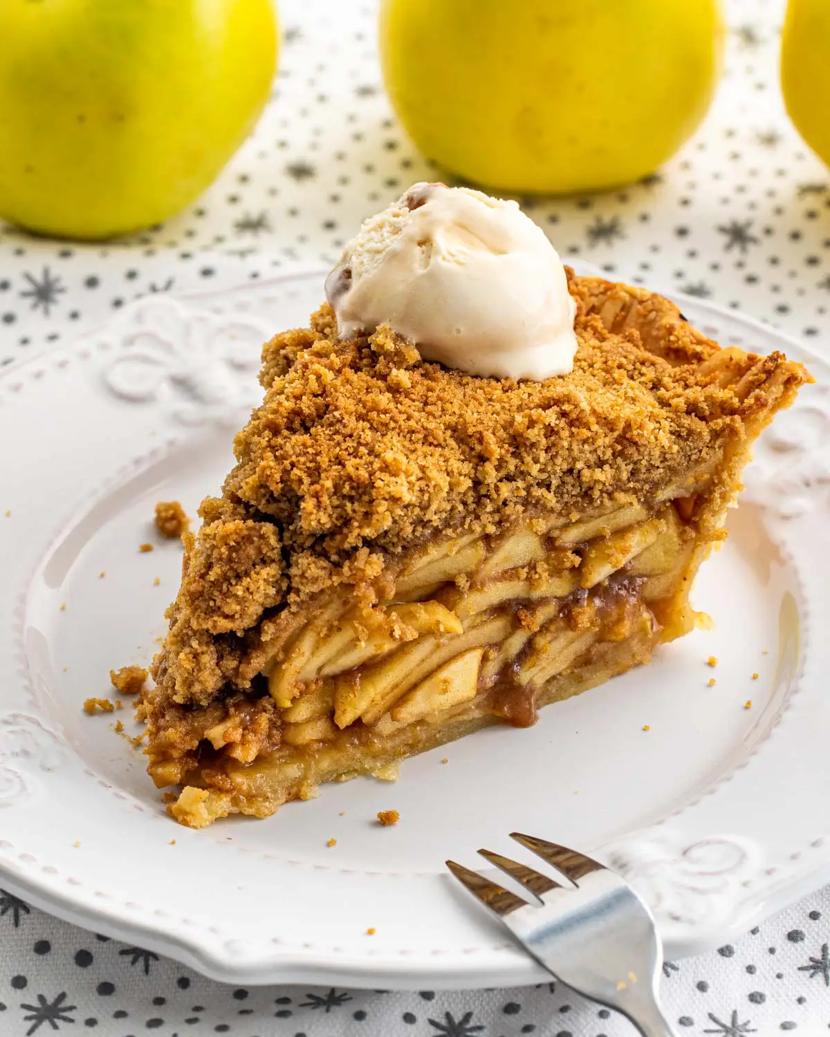 a gorgeous slice of dutch apple pie on a white plate.