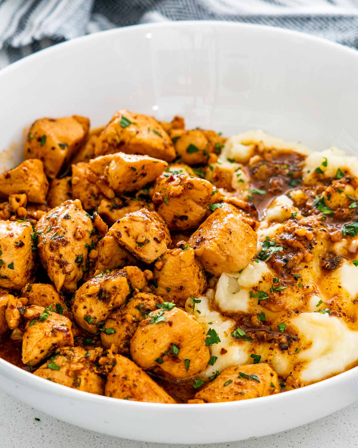 garlic butter chicken bites in a white plate with mashed potatoes.