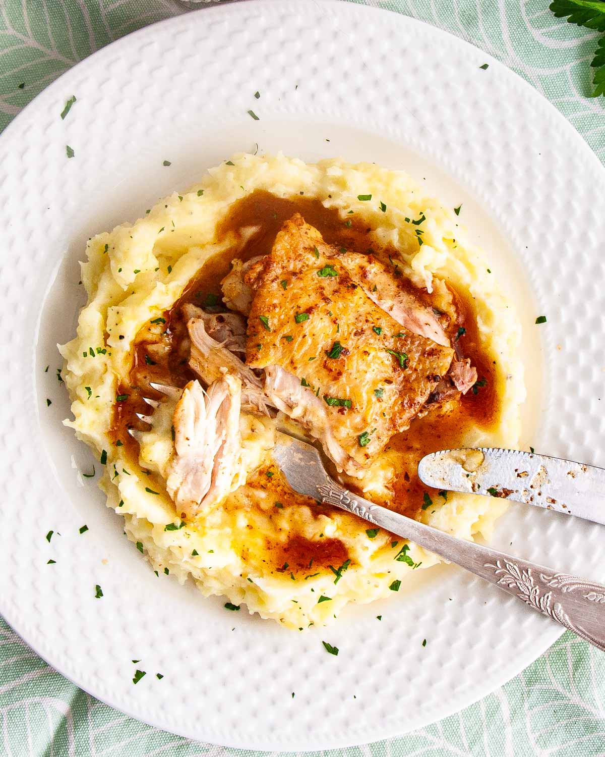 chicken thigh with gravy on a bed of mashed potatoes.