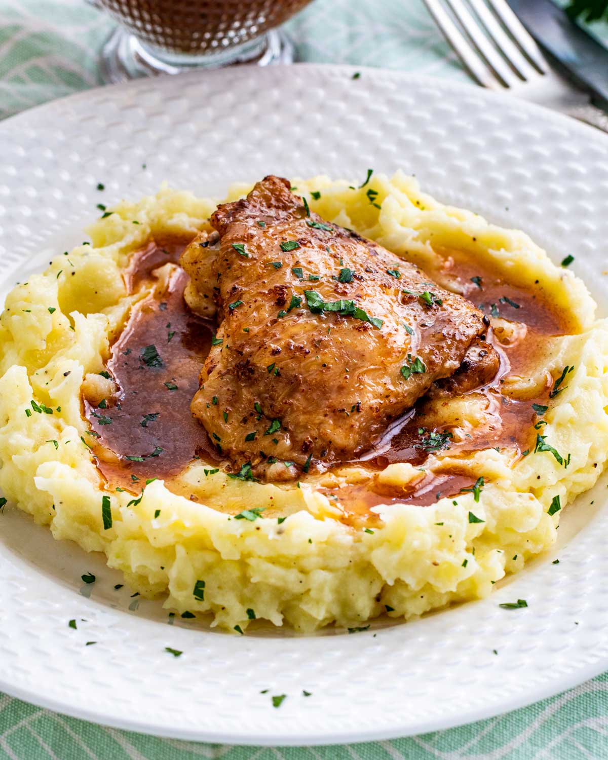 chicken thigh with gravy on a bed of mashed potatoes.