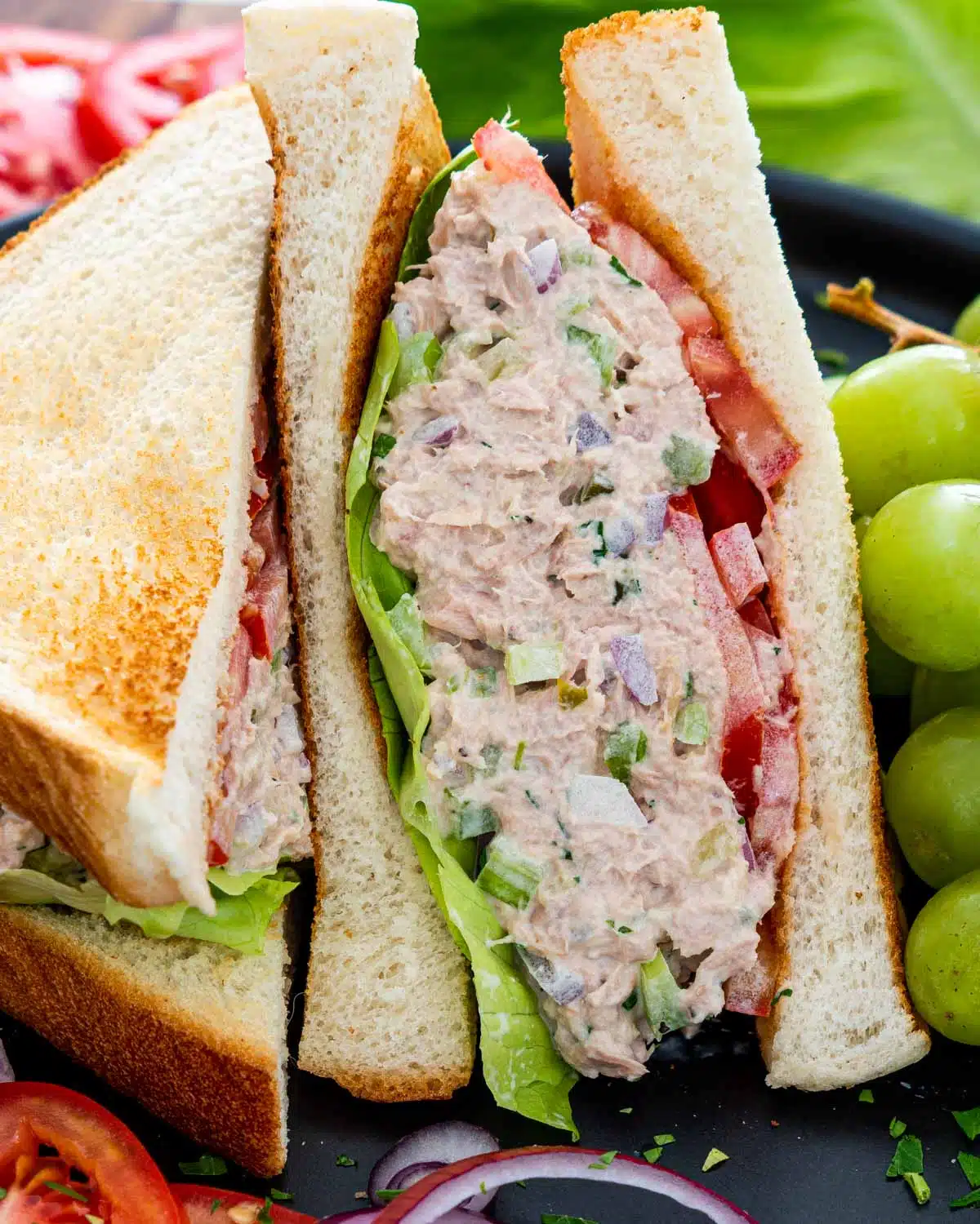 a tuna salad sandwich with lettuce and tomatoes.