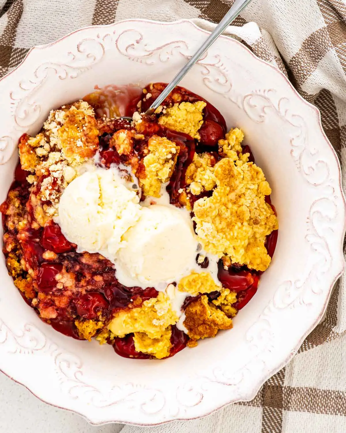 cherry dump cake in a plate with a scoop of ice cream.