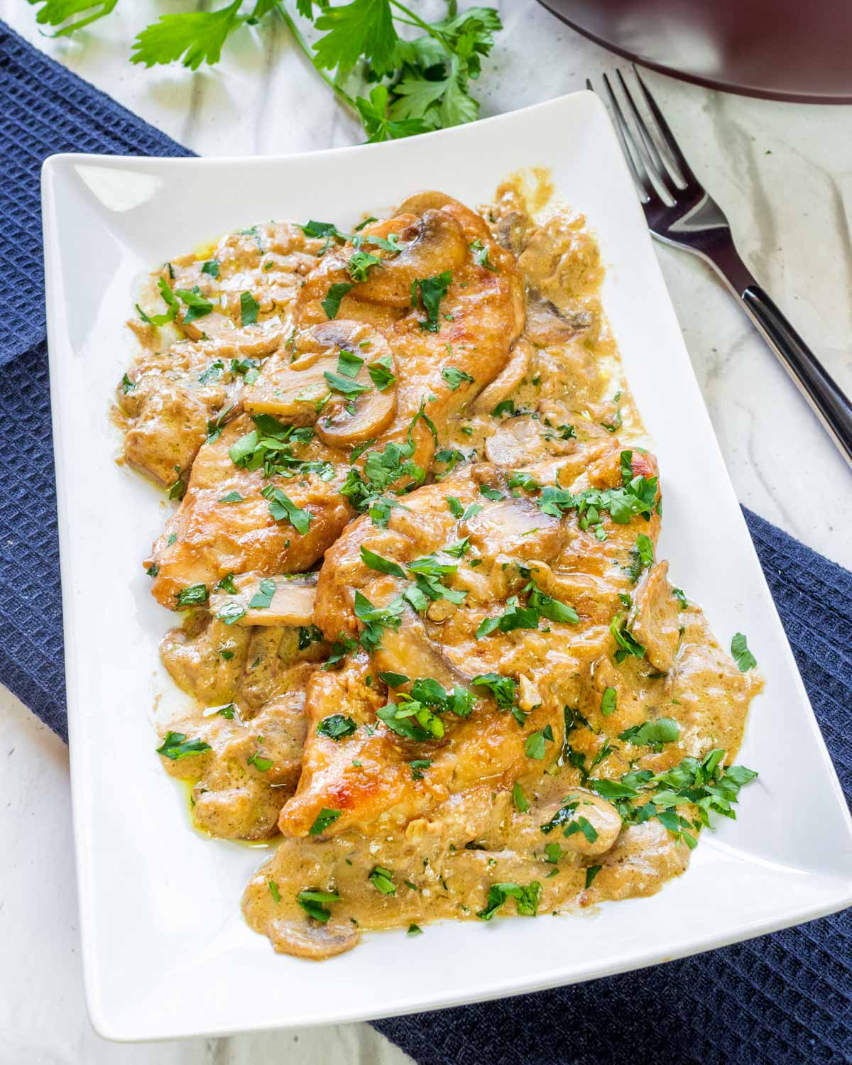 chicken marsala in a rectangular plate garnished with parsley.