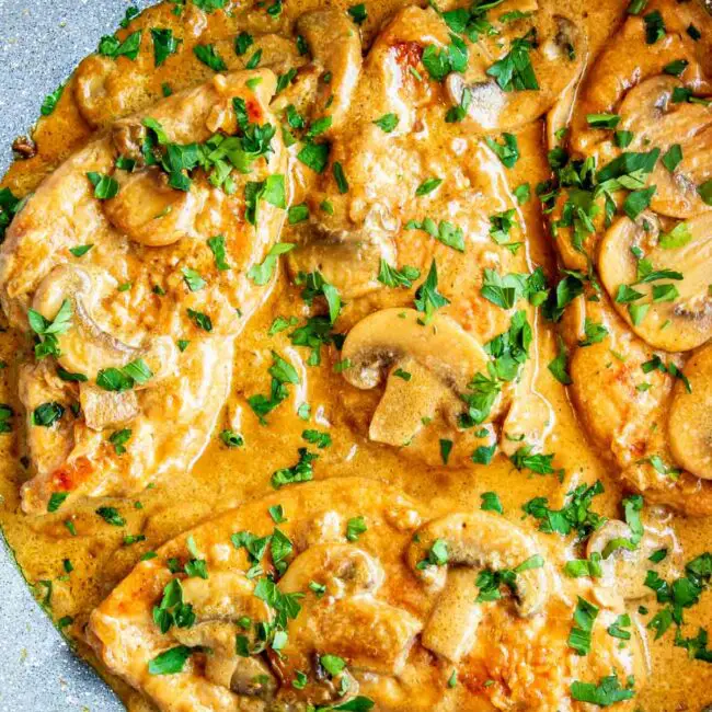chicken marsala with mushroom sauce and garnished with parsley in a skillet.