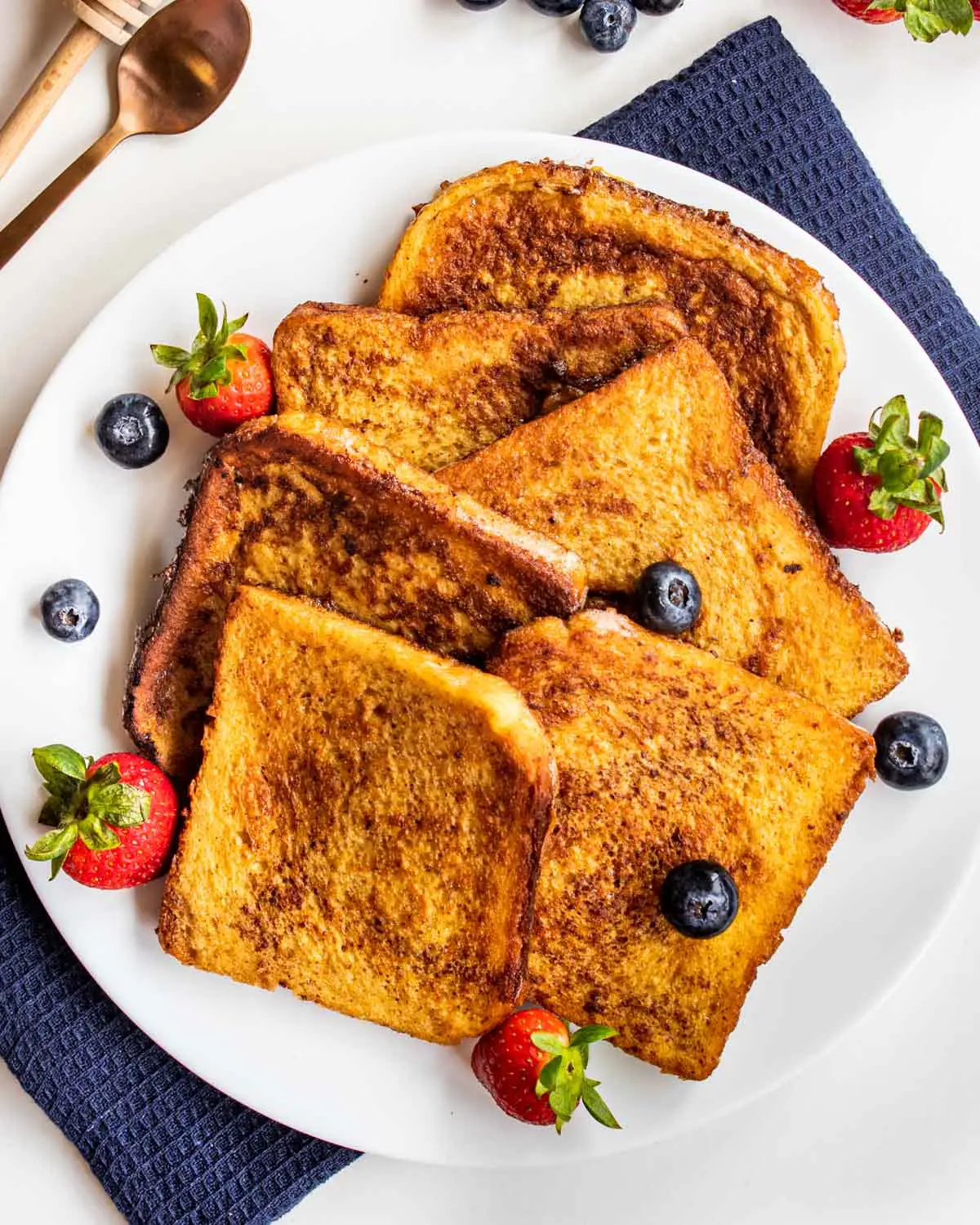 a bunch of slices of freshly made french toast with berries on a white plate.