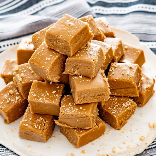 overhead shot of peanut butter fudge pieces on a plate garnished with crushed peanuts.