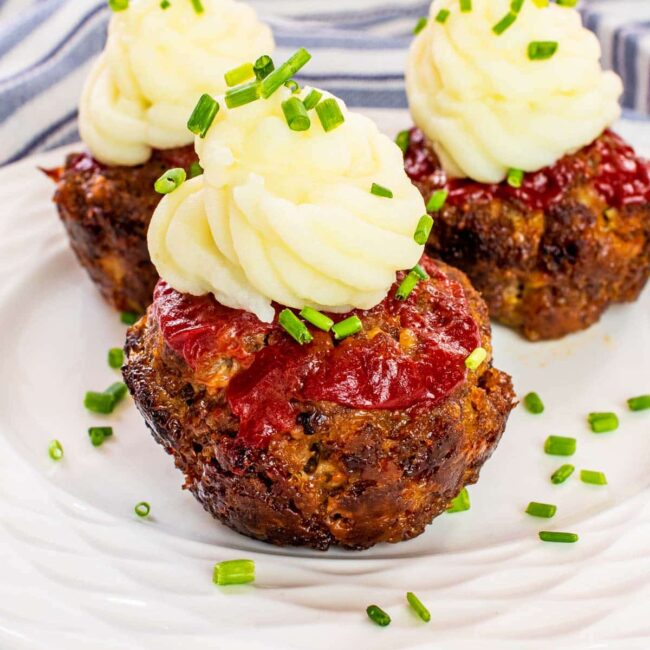 3 meatloaf muffins on a plate topped with mashed potatoes and ketchup.