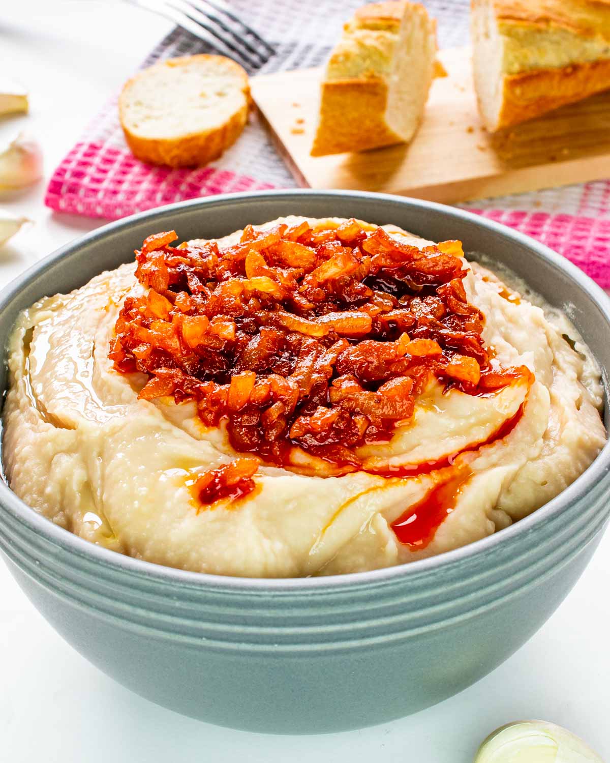 white bean dip with sauteed onions in a blue bowl.