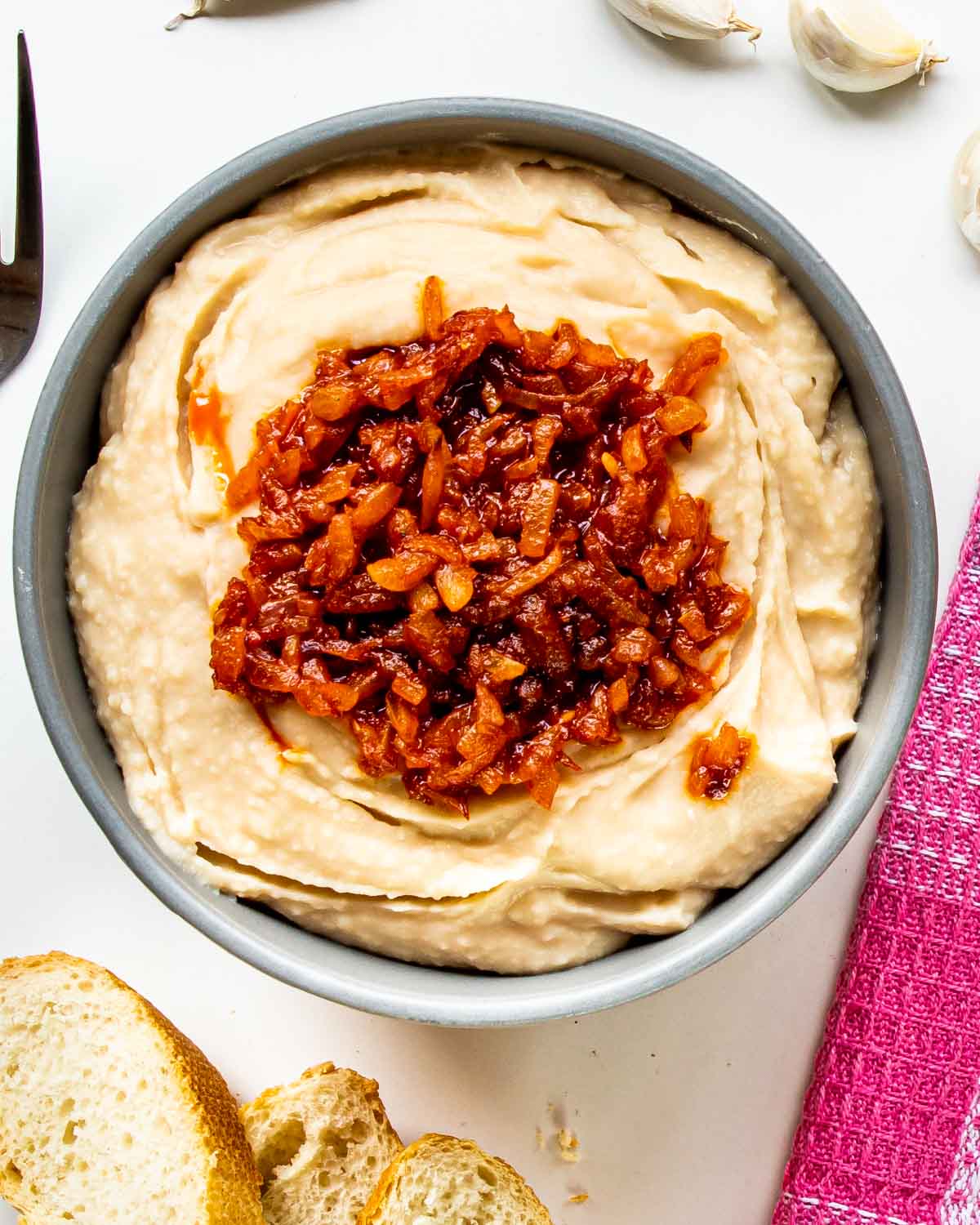white bean dip with sauteed onions in a blue bowl.