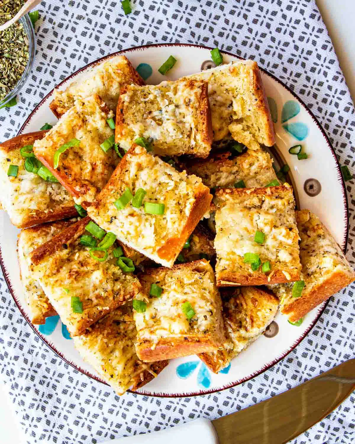 garlic bread cut up in slices on a plate garnished with green onions.