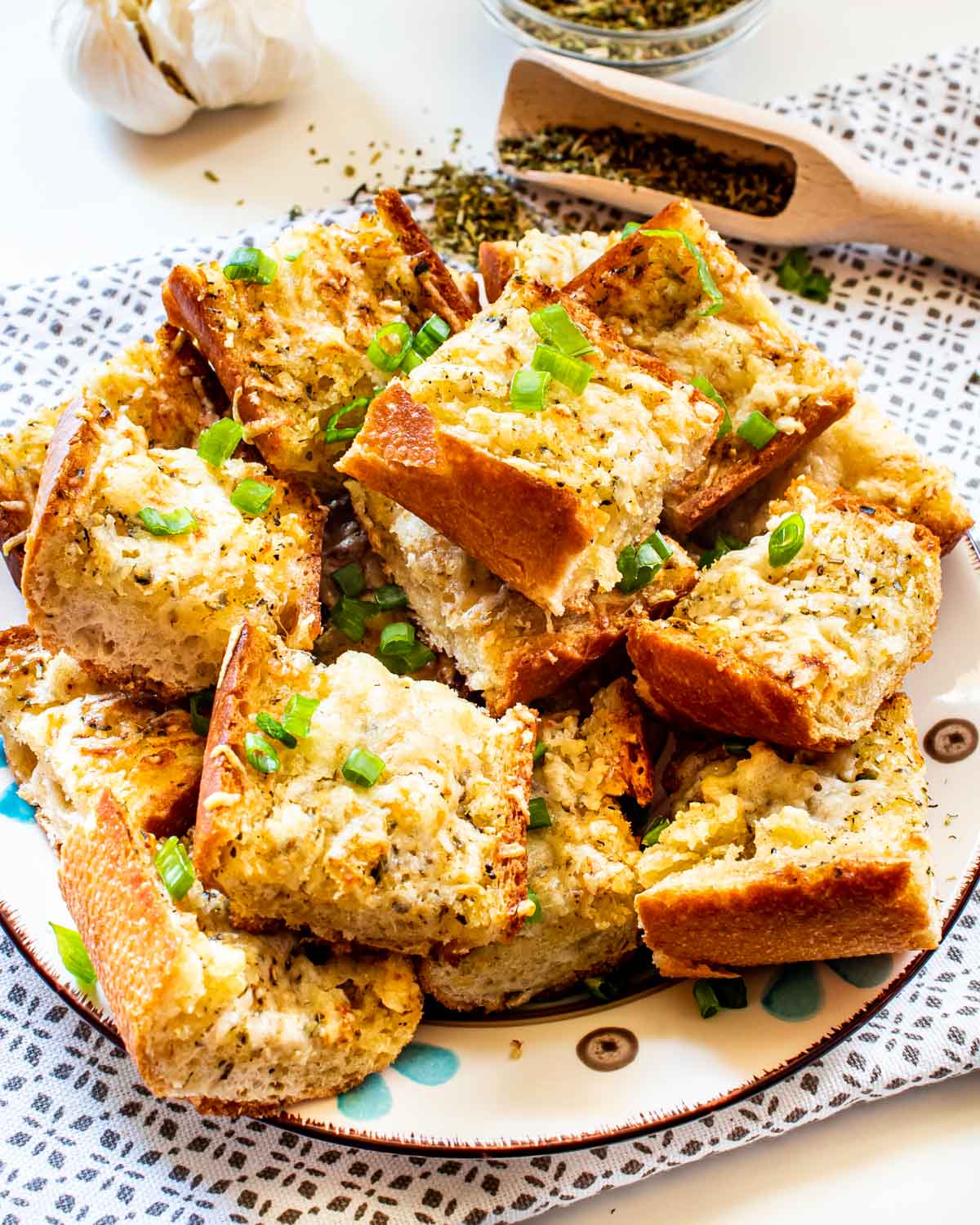garlic bread cut up in slices on a plate garnished with green onions.