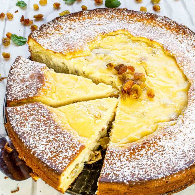 freshly baked ricotta cheesecake with 2 slices cut out.
